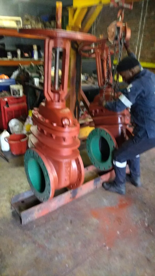 Technician working on a red flanged gate valve in a workshop