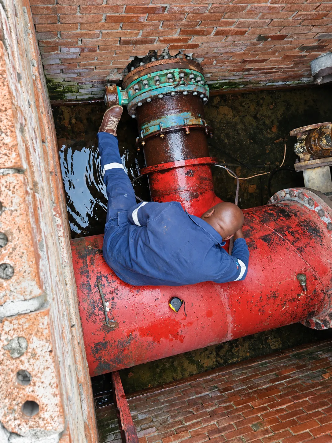 Technician working on a red pipeline inside a chamber